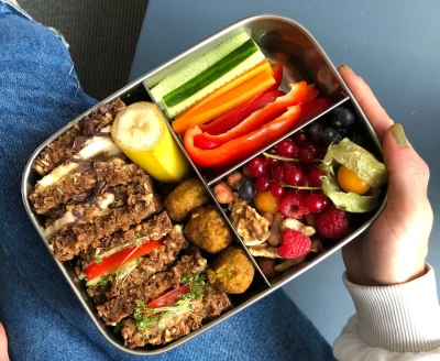 Eine Person hält eine Brotdose gefüllt mit gesundem Essen