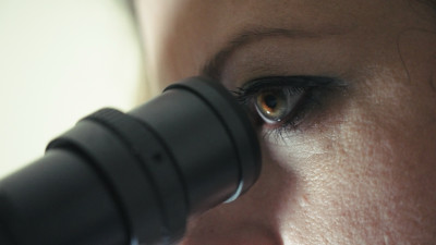 Eine Frau blickt in ein Mikroskop