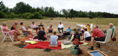 Menschen sitzen im Kreis auf einem Acker