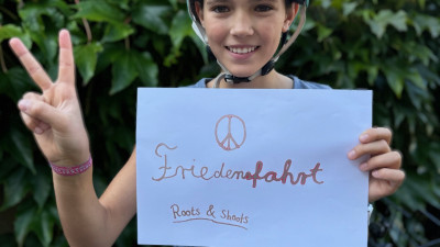 Ein Kinde streckt ein Plakat nach vorn mit dem Wort "Friedensfahrt"