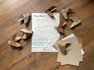 Origami Tauben und die Anleitung dazu liegen auf dem Boden