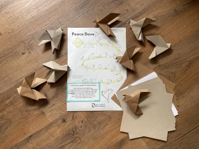 Origami Tauben und die Anleitung dazu liegen auf dem Boden