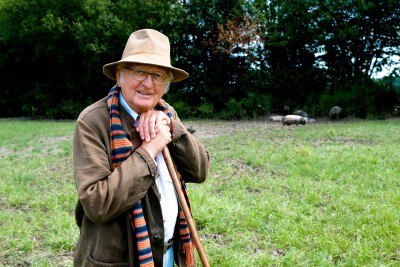 Ein Mann steht auf einen Stock gestützt in einem Feld