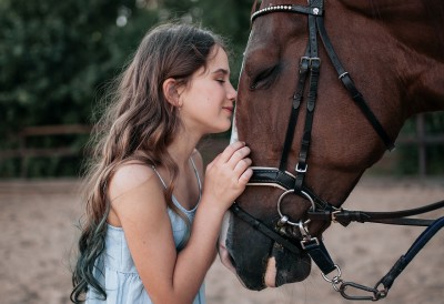 Eine junge Frau kuschelt mit einem Pferd